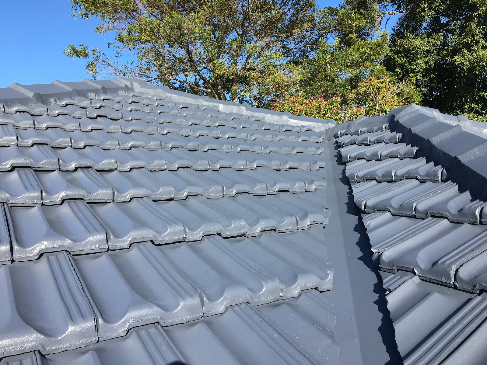 Freshly coated grey roof tiles against a blue sky