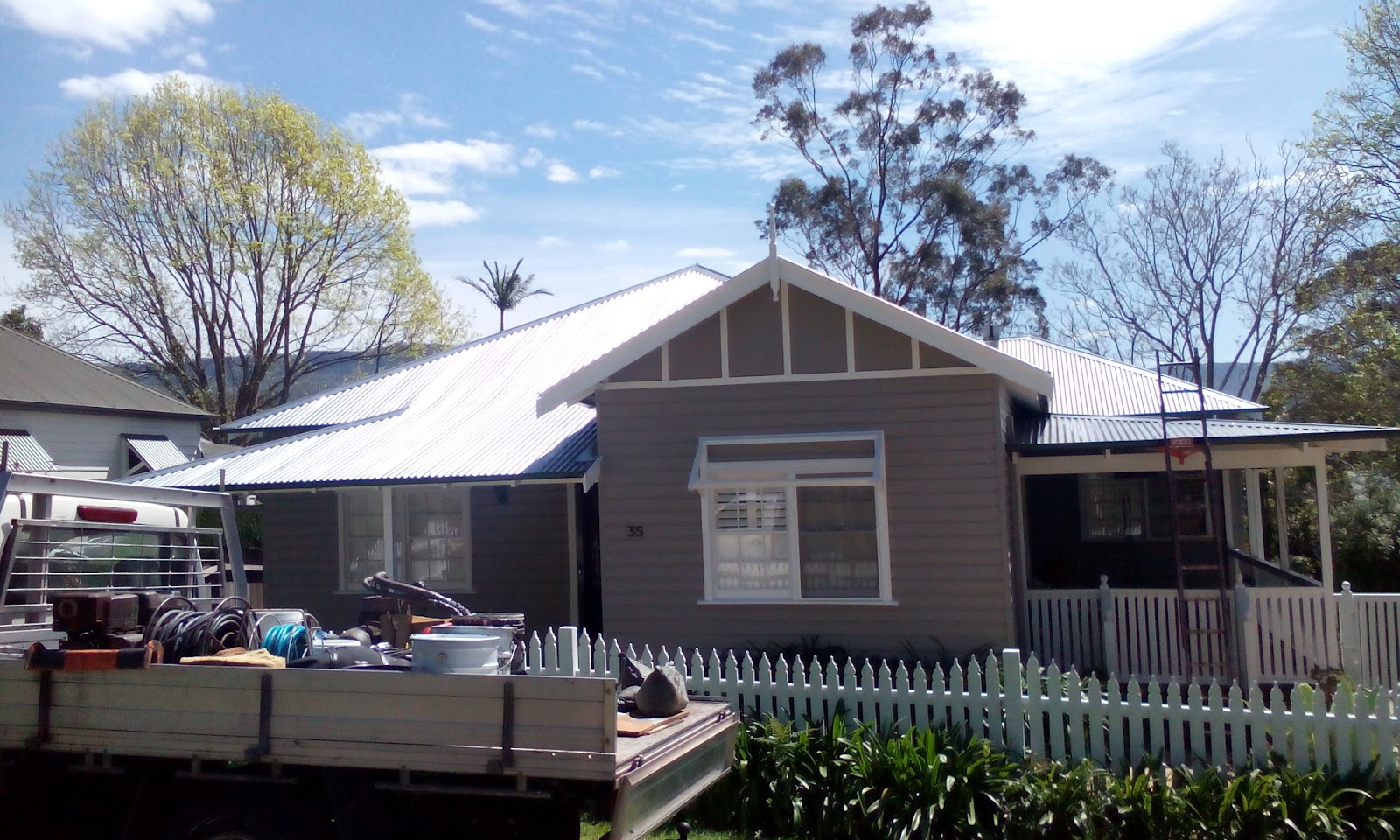 Weatherboard cottage with a white metal roof and the work ute out front